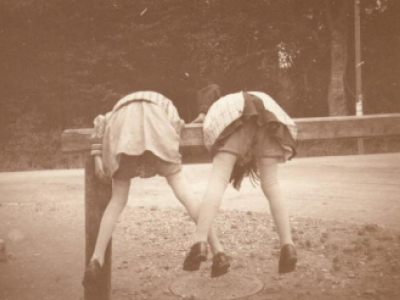 Billedet forestiller to piger, der klatre på den bom, der var  udenfor Louis Kettners forretning til at tøjre heste ved. 