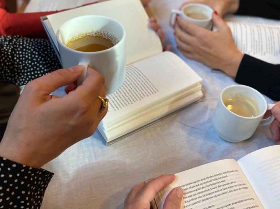 Fotografi af personer der sidder med kaffekopper og bøger